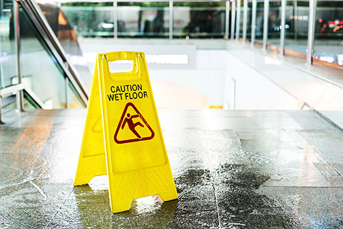 caution wet floor sign on wet tile floor near stairs to prevent slip, falls and other workplace injuries