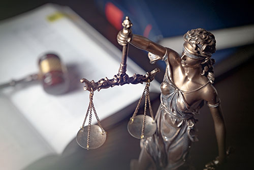 lady justice with scales in front of a law book talking about a subpoena and a warrant with gavel
