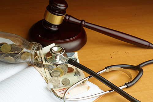 judge's gavel, money, stethoscope, and paperwork for court case